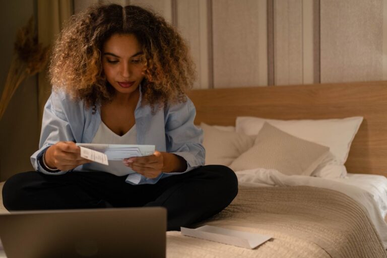 woman sitting on bed looking at healthcare documents